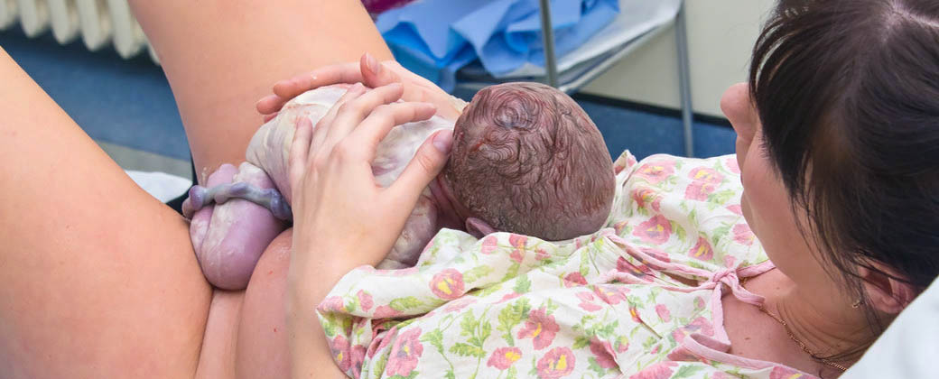 Persona recién nacida sobre el vientre de su madre que todavía conserva el cordón umbilical. Créditos: Bebés y más