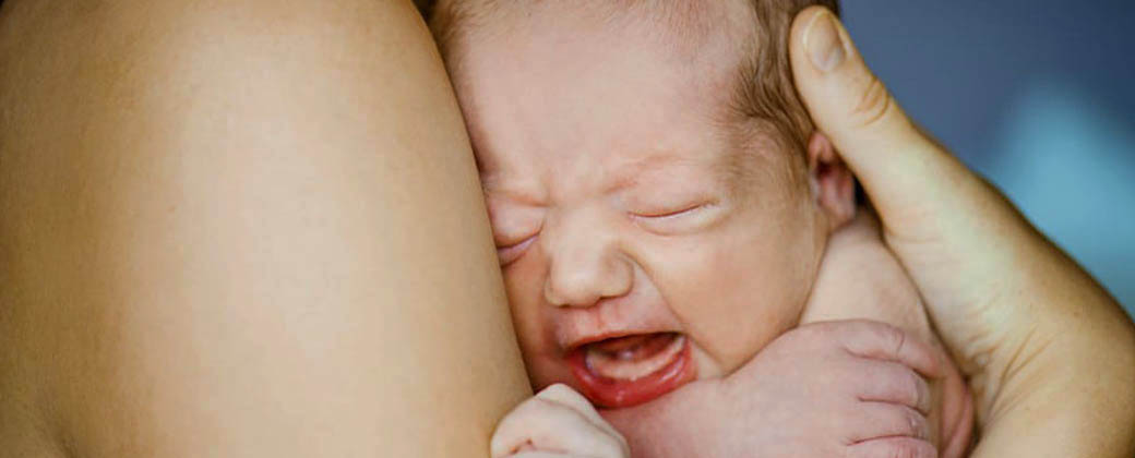 Un bebé llora apoyado sobre su madre. Créditos: Etapa infantil