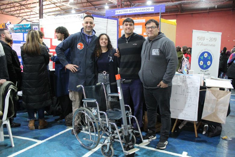 Los estudiantes posan junto a sus docentes y la silla en la Feria. Créditos: Nicolás Retamar / Agencia de Noticias Científicas UNQ.