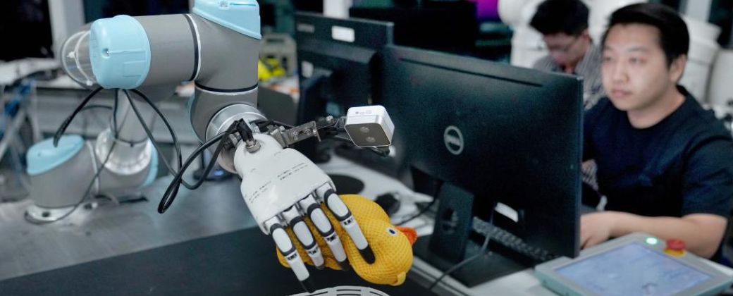 Un trabajador de China usa un robot para agarrar objetos. Créditos: Lin An / Xinhua.