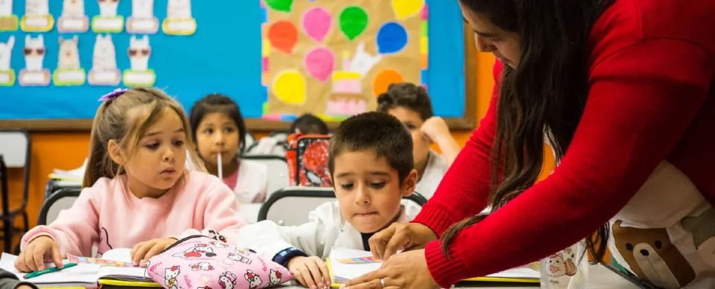Dos estudiantes prestan atención a la indicación de su maestra. Créditos: Chequeado.